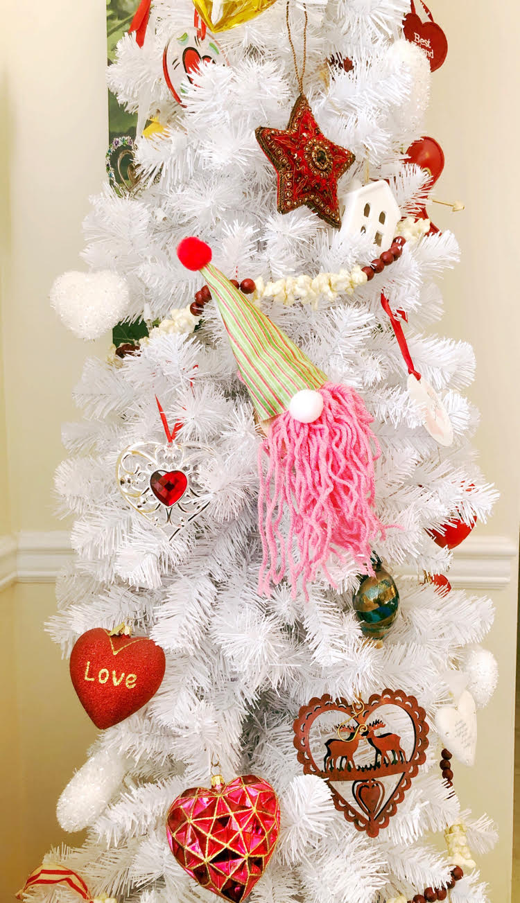 A white Christmas tree decorated with DIY gnome ornaments and hearts for Valentine's Day.