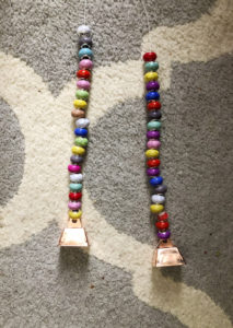 String of beads with a cow bell for a DIY wind chime