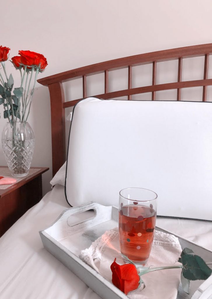 Cooling memory foam pillow on a farmhouse style bed with a crystal vase of roses on a bedside table.