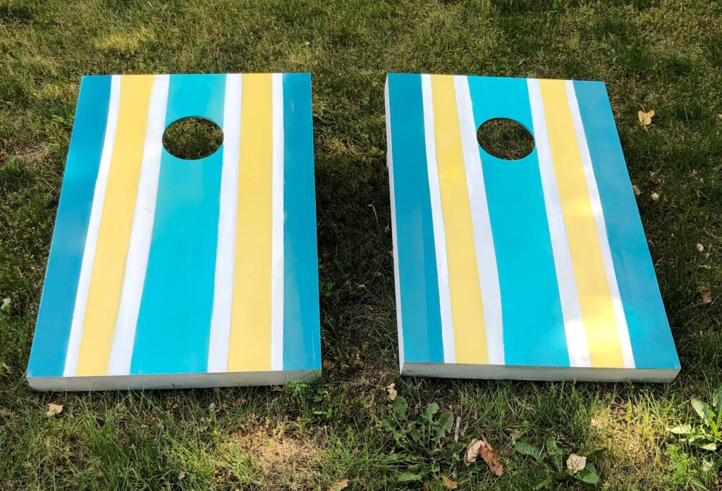 DIY spray painted corn hole boards  with blue and yellow stripes