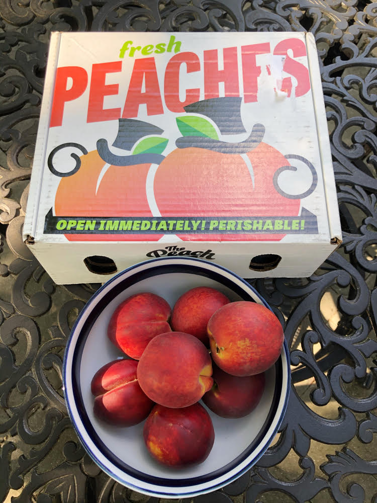 fresh peaches in a bowl on a wrought iron patio table