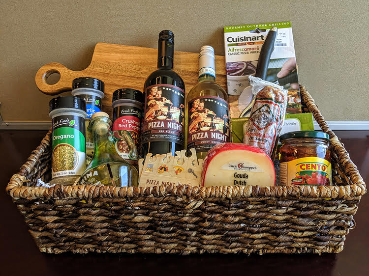 A pizza night gift basket idea by Theme Night Wines. The basket is filled with ingredients and supplies for making homemade pizza.