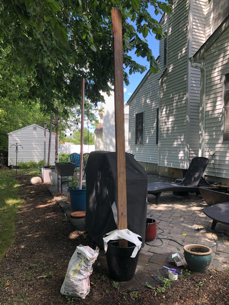 A pole set in quick setting cement to hold string lights. The pole is temporary held upright with some Duck tape while the cement hardens