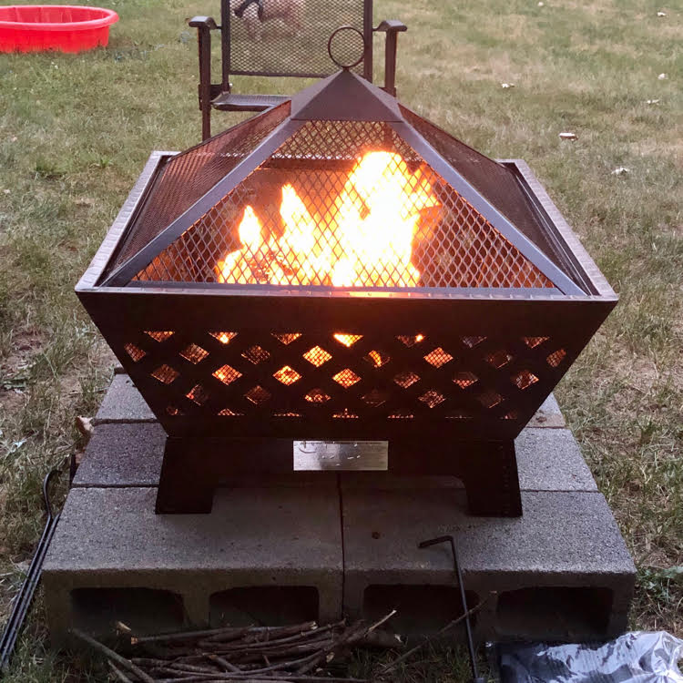 Fire burning in a Landmann antique bronze fire pit in a backyard