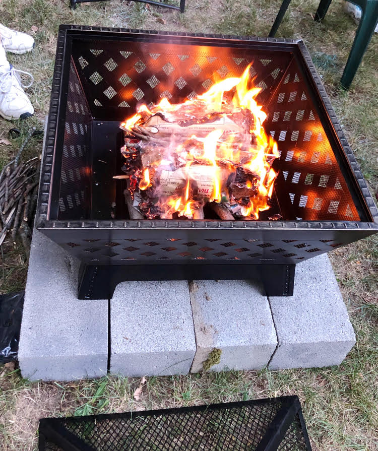 a metal fire pit sitting on a base of concrete blocks