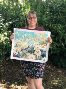 Woman holding a completed paint by numbers painting of daisies