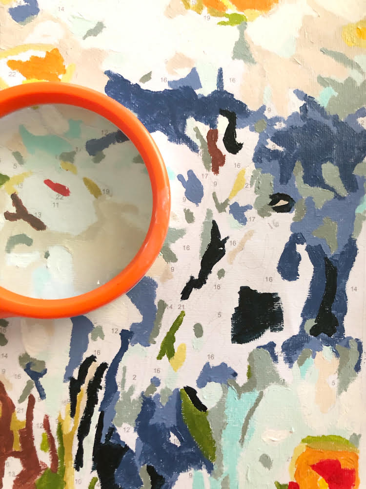 close up shot of a paint by numbers canvas magnified by an orange magnifying glass