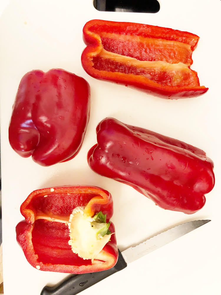 halved red peppers on a white cutting board