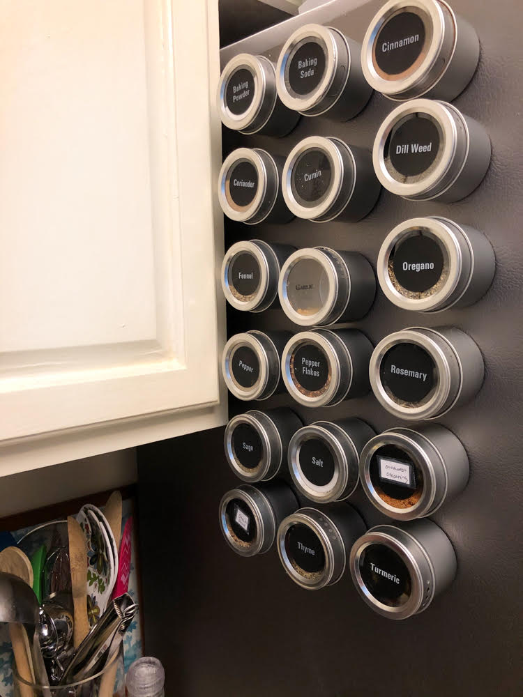 spices in magnetic tins on the side of a refrigerator