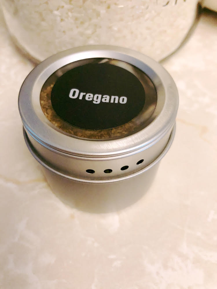 A magnetic spice tin of oregano with a printed chalkboard label