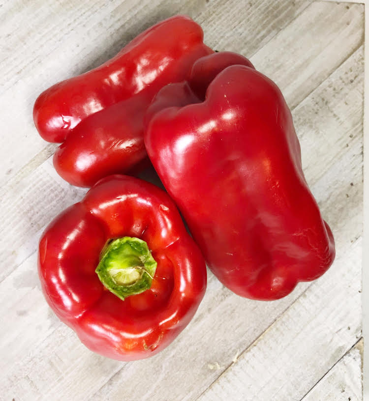 fresh red peppers on a wood cutting board