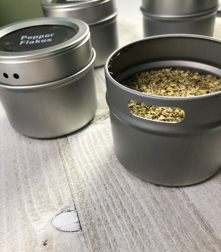 refillable magnetic spice tins, one filled with oregano and one filled with red pepper flakes