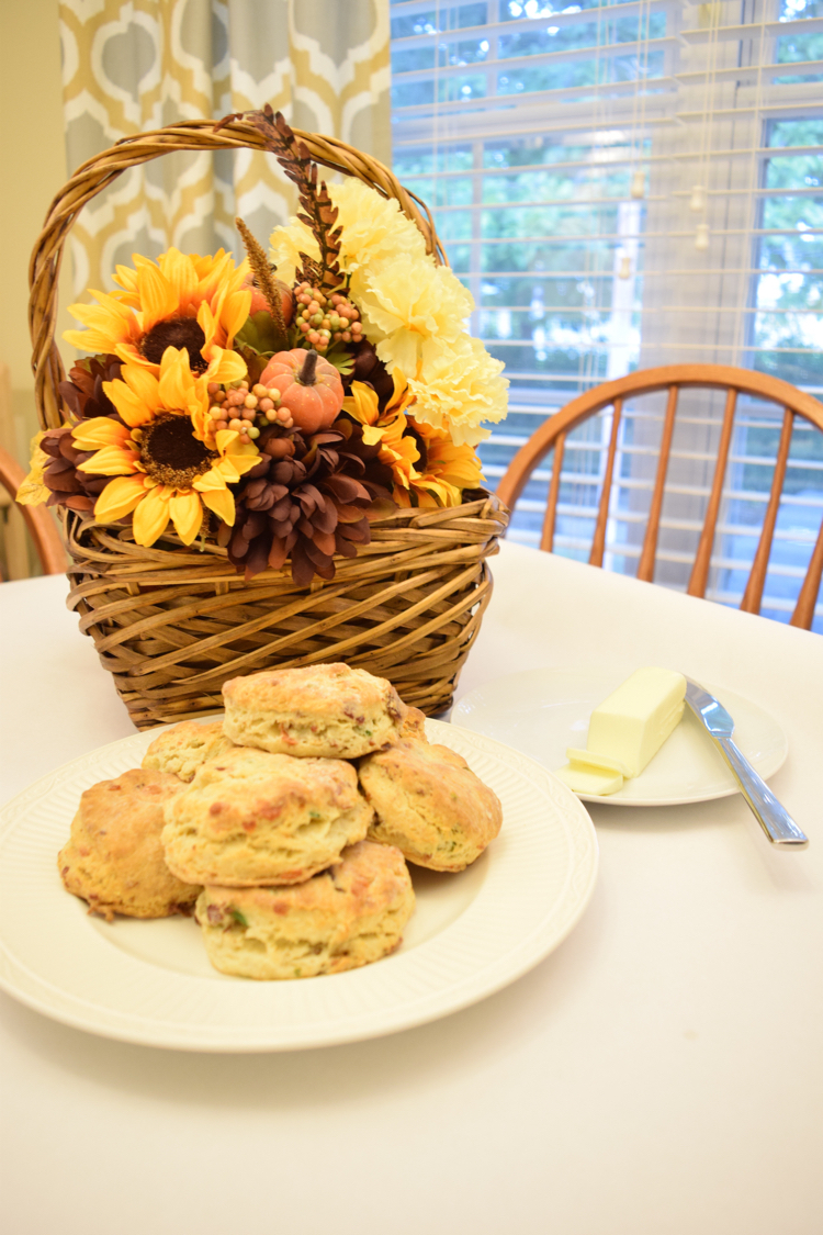 Bacon cheddar bacon and chive biscuits on a plate in front of plate with faux fall flowers