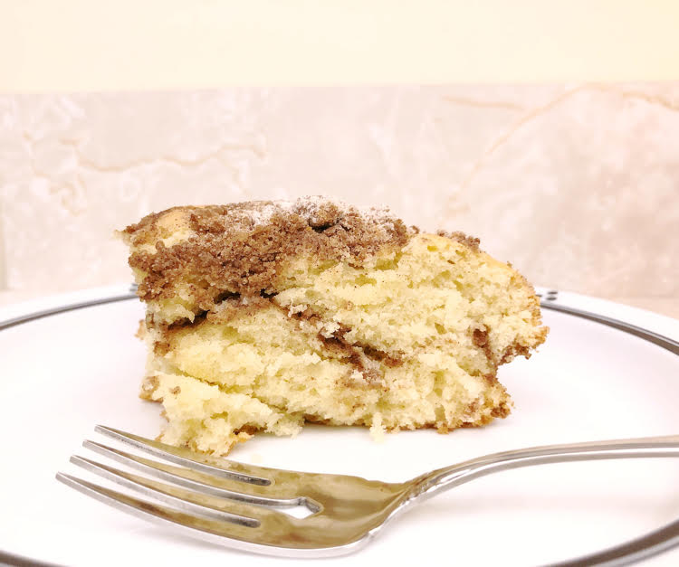 a piece of cinnamon crumb cake on a white plate with a fork