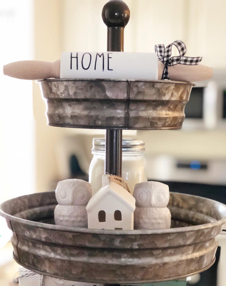 a cute tiered tray in a kitchen, decorated with a mini "home" rolling pin, white owl salt and pepper shakers and a white ceramic mini house