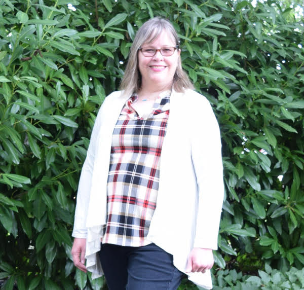 woman wearing white cardigan, plaid top and dark wash jeans