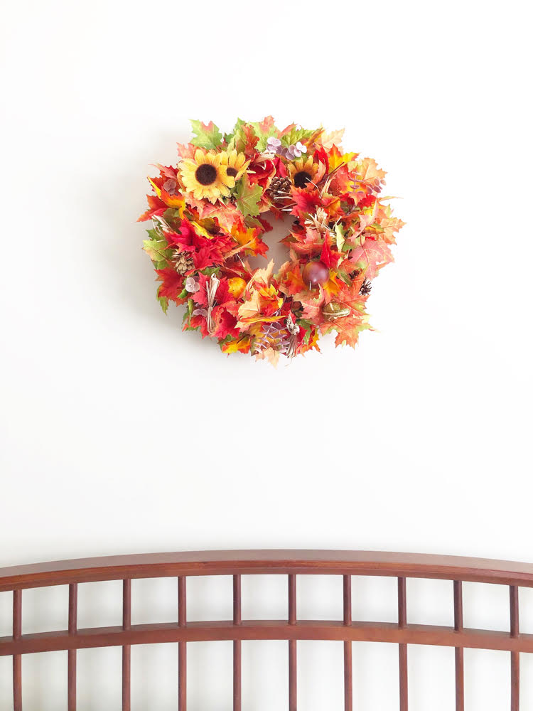 Fall leaf wreath over a farmhouse-style bed