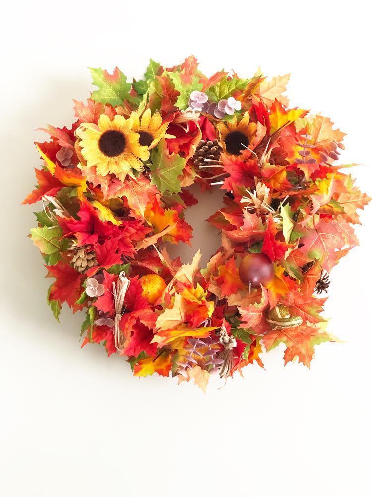 a beautiful fall leaf wreath with sunflower accents