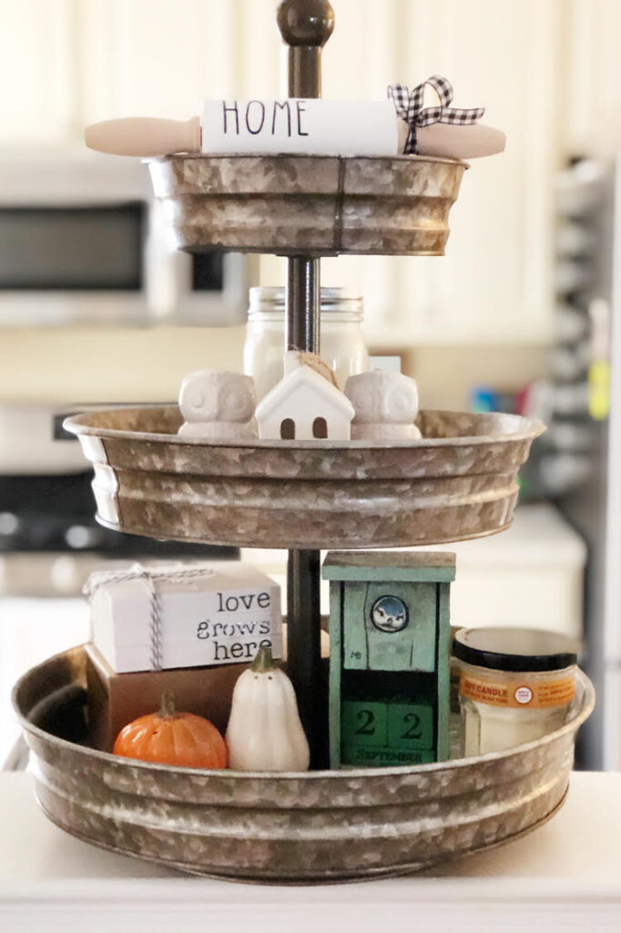 A tiered tray in a kitchen.  On the tray are items like decorative salt and pepper shakers
