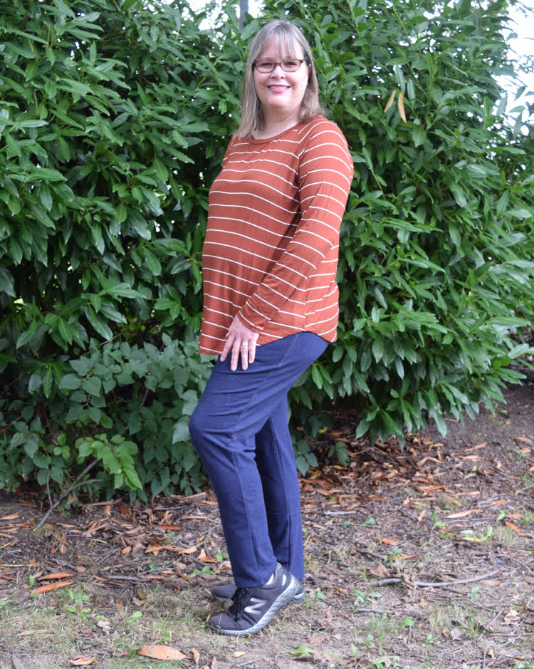 woman wearing an orange shirt with white stripes, and navy sweatpants