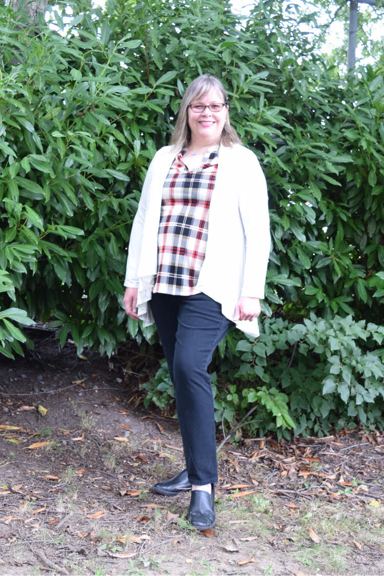 woman wearing plaid top, dark wash jeans and an open white cardigan