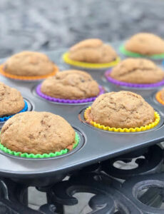 banana chocolate chip muffins in rainbow colored silicone cupcake liners in a muffin tin