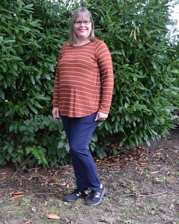 woman wearing an orange top with white stripes and navy blue sweatpants