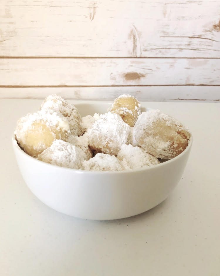 a bowl of zeppole made in an air fryer and dusted with powdered sugar