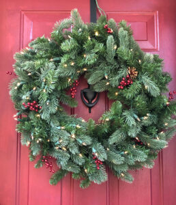 beautiful faux evergreen wreath on a vibrant red door