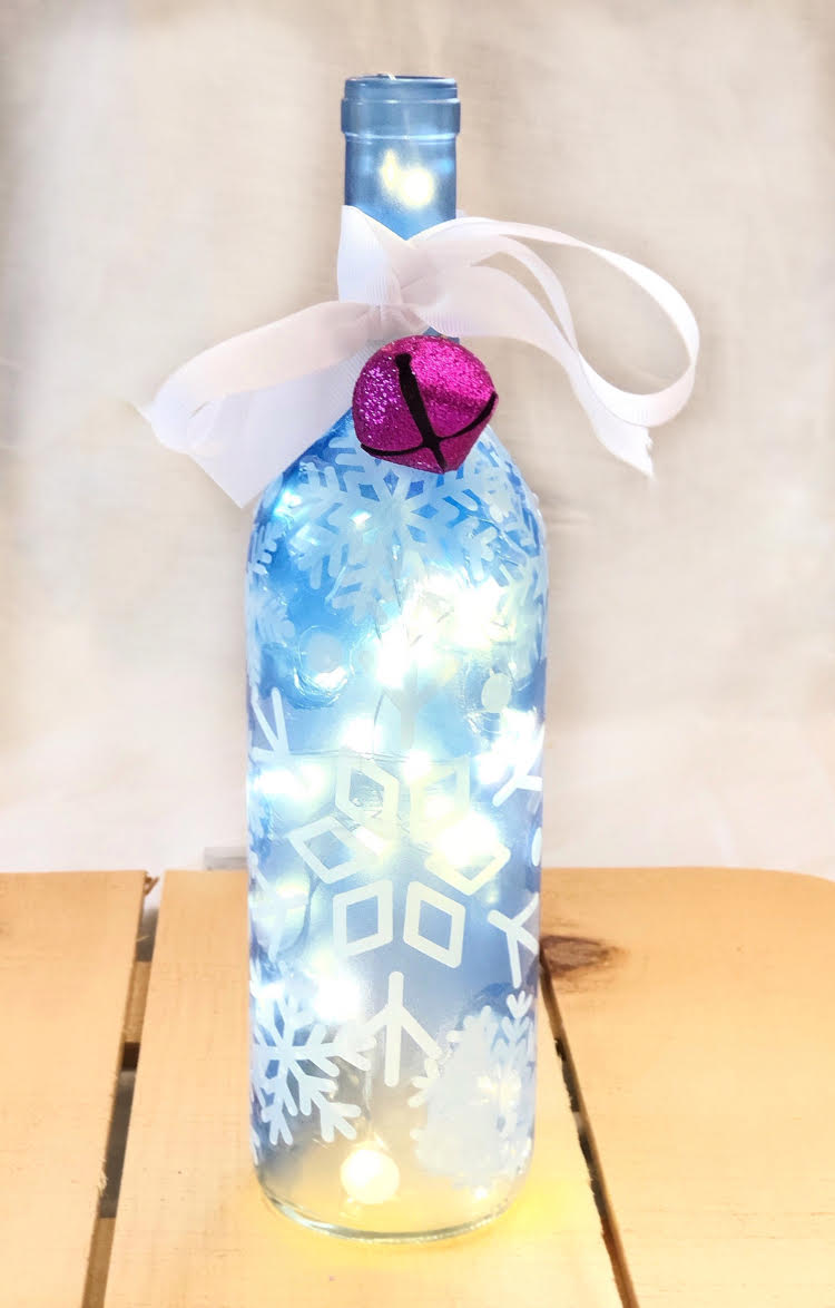 A homemade Christmas gift idea - a DIY lighted wine bottle decorated with snowflakes.