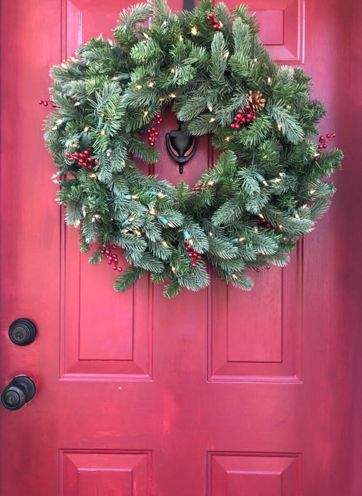 lighted evergreen wreath on a red door