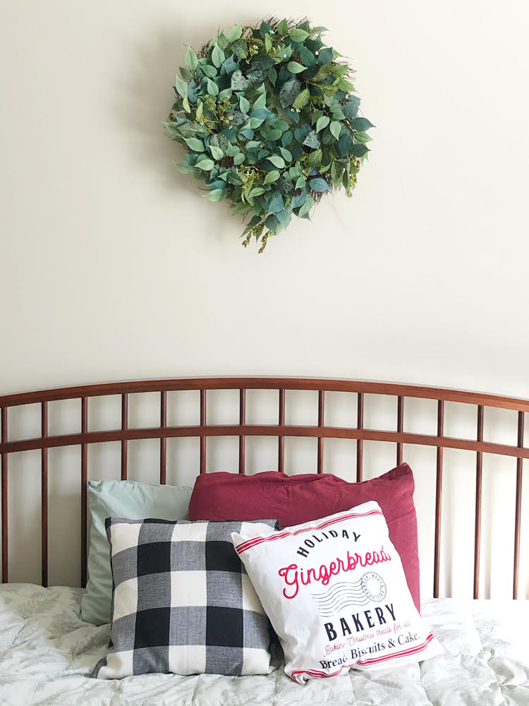 beautiful faux leaves and berries wreath for the Christmas and holiday season over a pretty farmhouse style bed