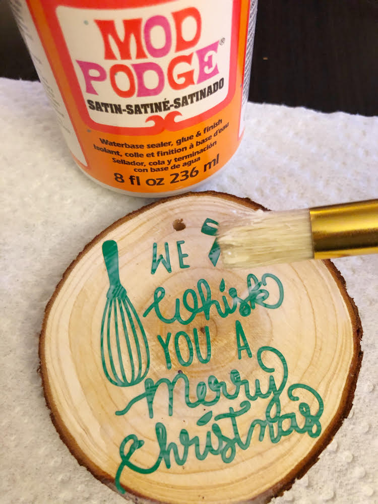 adding Mod Podge to a DIY wood slice ornament with a Silhouette Cameo vinyl design