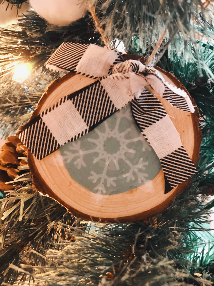 rustic wood slice snowflake ornament hung in a Chrstmas tree.