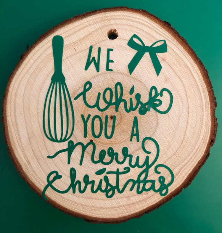 a homemade "We Whisk You a Merry Christmas" wood slice ornament