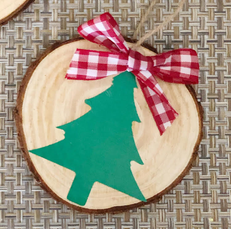 a handmade wood slice ornament decorated with a vinyl Christmas tree and a red and white buffalo plaid ornament