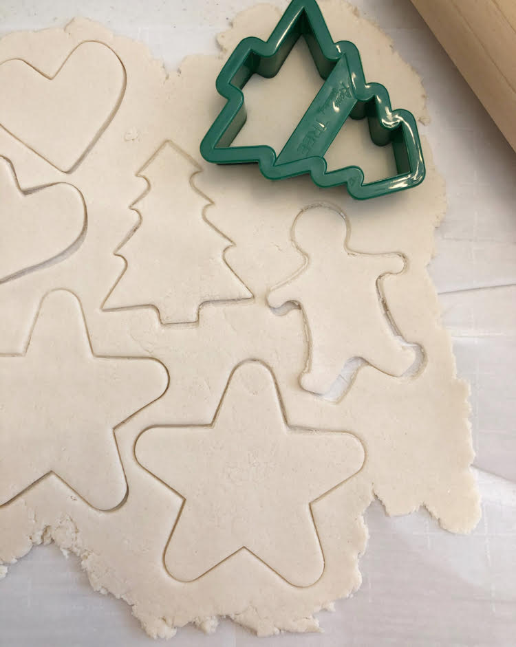 cutting dough with cookie cutters to make salt dough ornaments for Christmas and the holidays