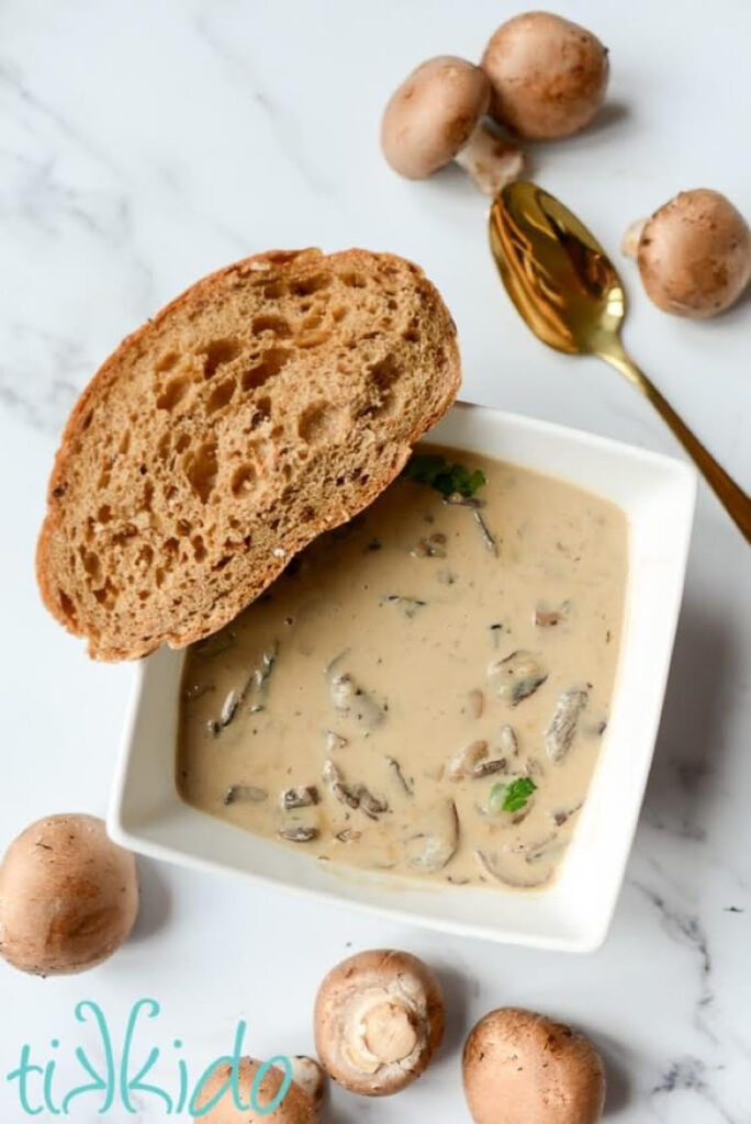 a bowl of homemade cream of mushroom soup with a slice of bread