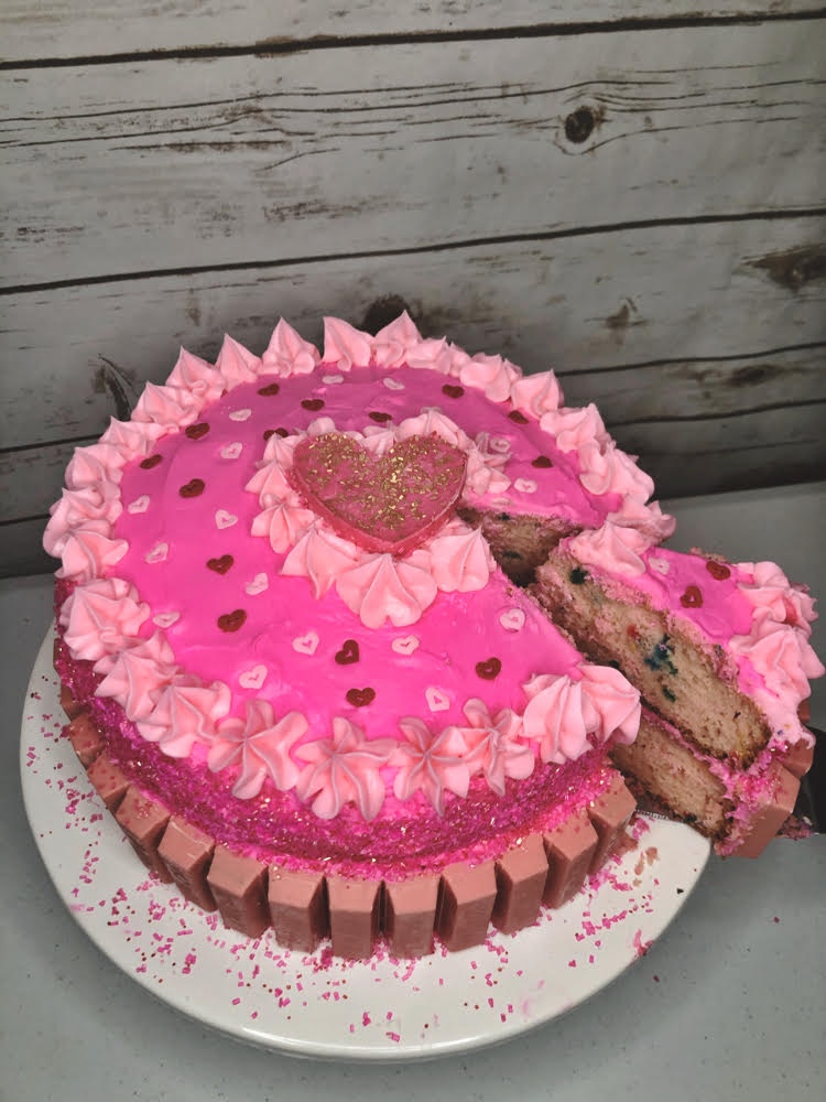 a slice being taken out of a pink homemade KitKat cake