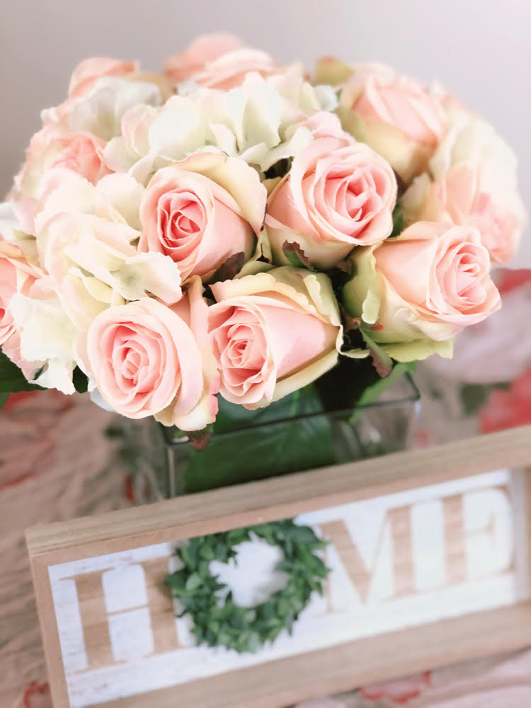 Sweet glass vase filled with faux roses and hydrangea with a farmhouse home sign