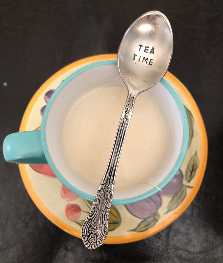 tea time engraved spoon placed across a mint green tea cup