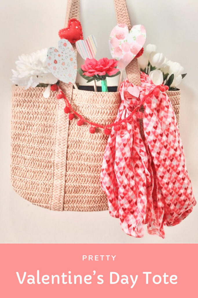 Valentine's Day straw bag with paper and felt hearts, a mini pom pom garland, faux flowers and a Valentine's Day scarf