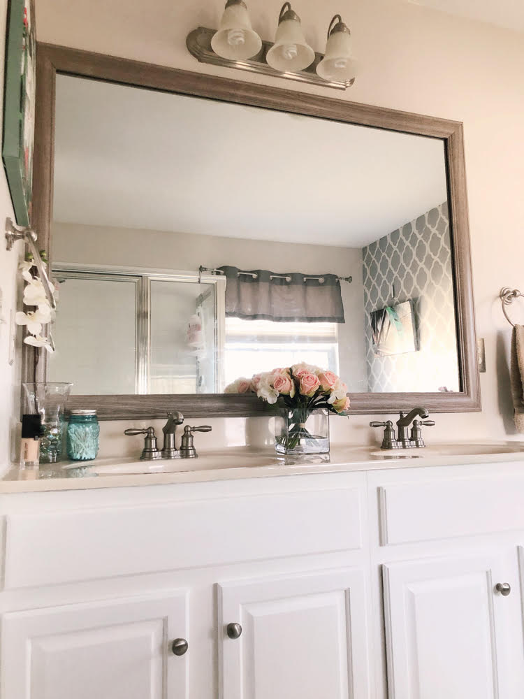 a bathroom mirror framed with a MIrrorChic frame; a painted bathroom vanity