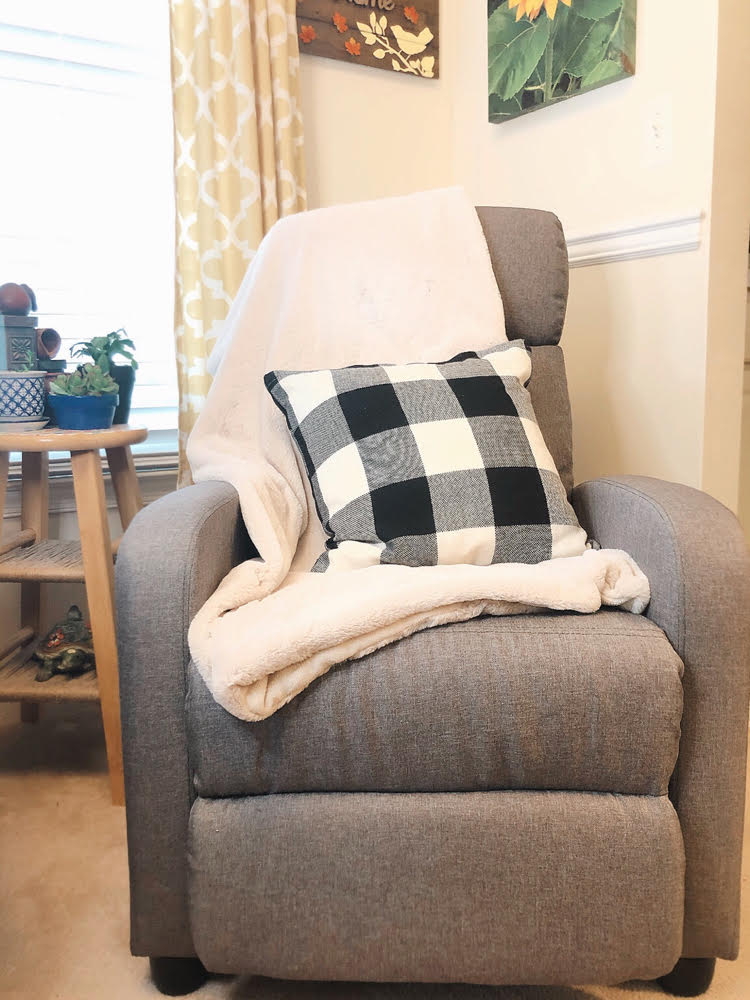 beautiful gray recliner tray with a white fuzzy blanket and a black and white buffalo check pilow