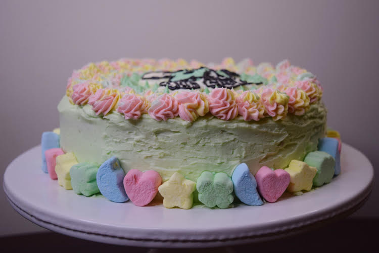 cake decorated with green icing, rainbow piped stars and Lucky Charms marshmallows