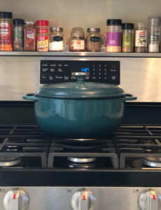 stoveshelf, a handy magnetic shelf for the top of a stove, and a green Dutch oven on a rangetop