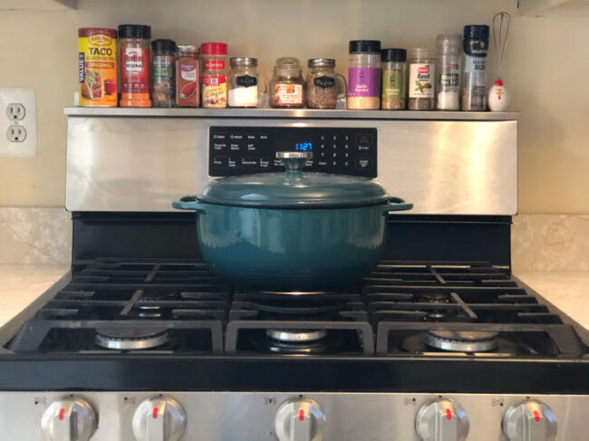 stoveshelf, a handy magnetic shelf for the top of a stove, and a green Dutch oven on a rangetop