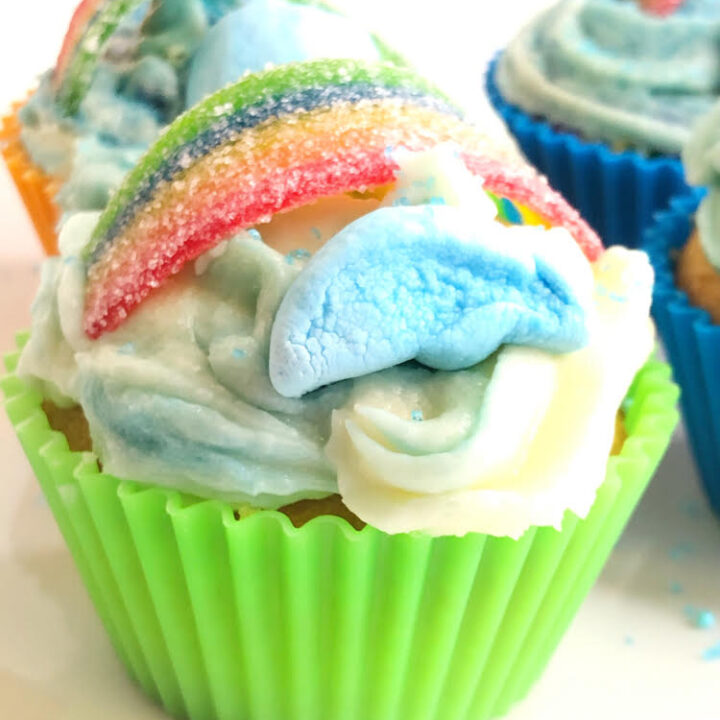 buttercream cupcake in silicone cupcake cup, topped with Lucky Charm marshmallow clouds and a candy rainbow