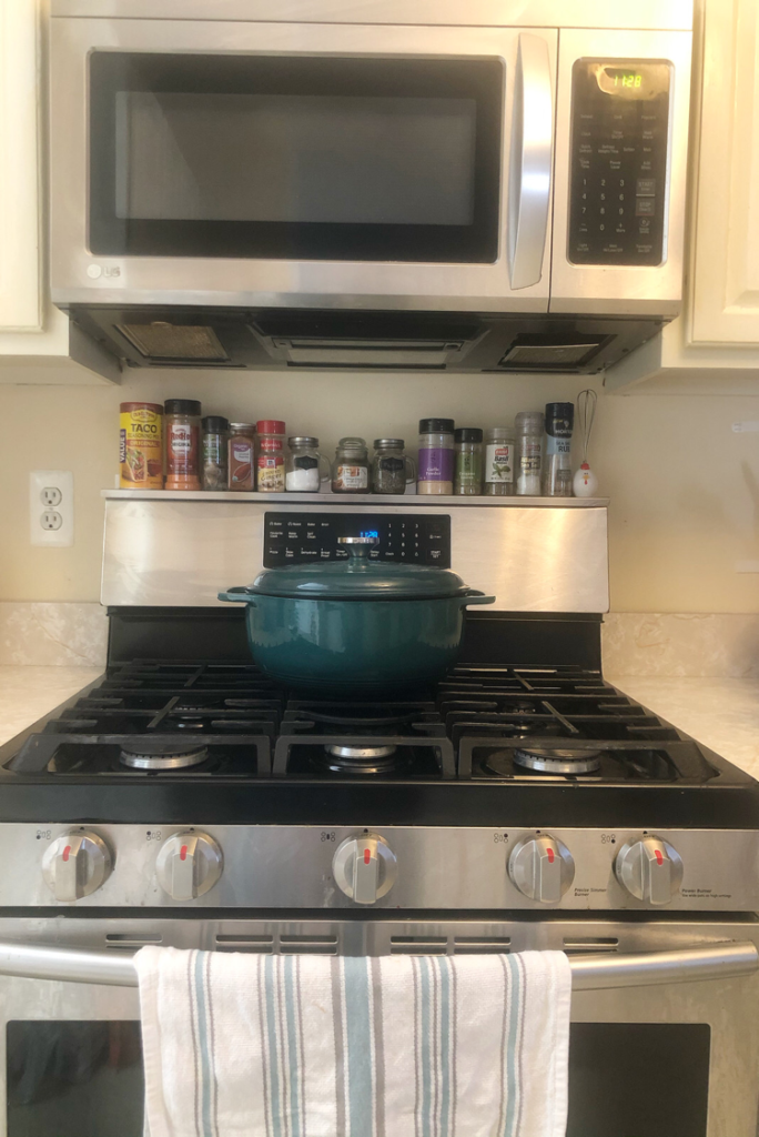 a stainless steel stove topped with Stoveshelf, an inexpensive magnetic shelf that can be placed on top of a stove