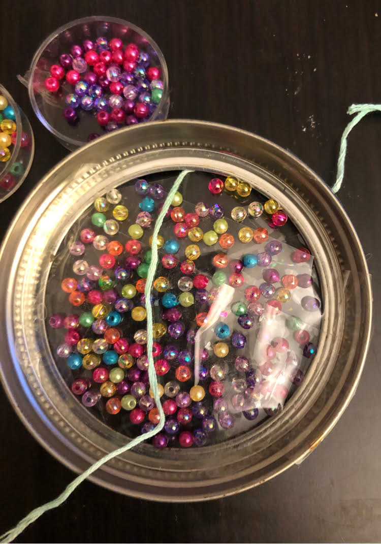 crafting an easy DIY suncatcher with beads and a mason jar ring, plus tape